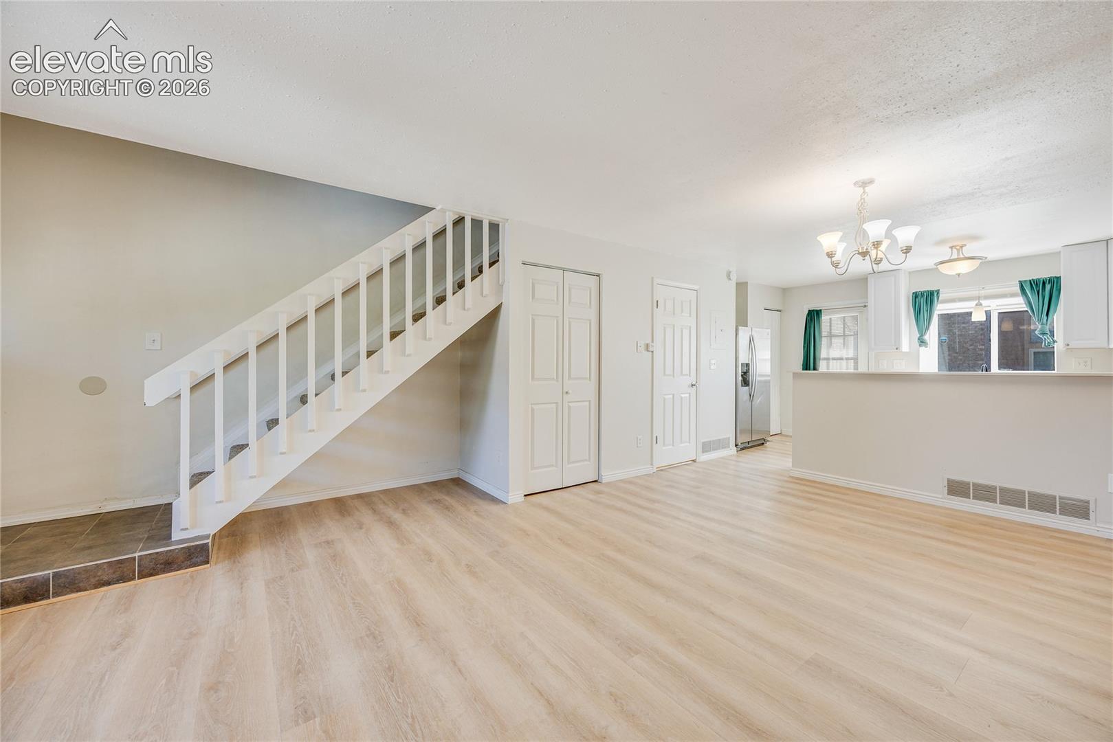 Light wood-finish flooring throughout, white painted staircase, and white interior doors