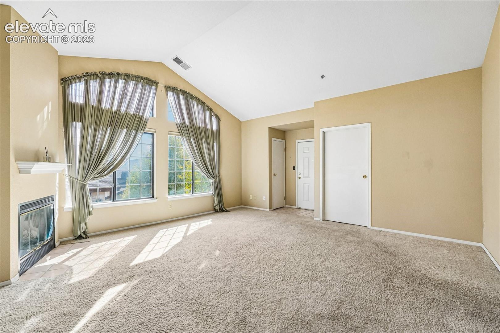 Living room with vaulted ceilings, a gas fireplace, a walk out and large windows brining in tons of natural light