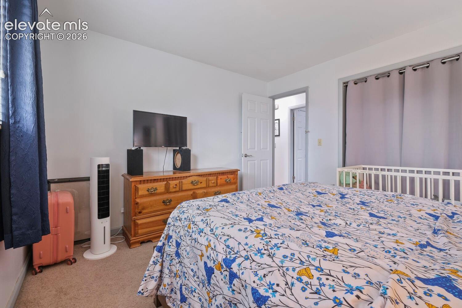 Carpeted room with white walls, a white paneled door, and a window with dark blue curtains