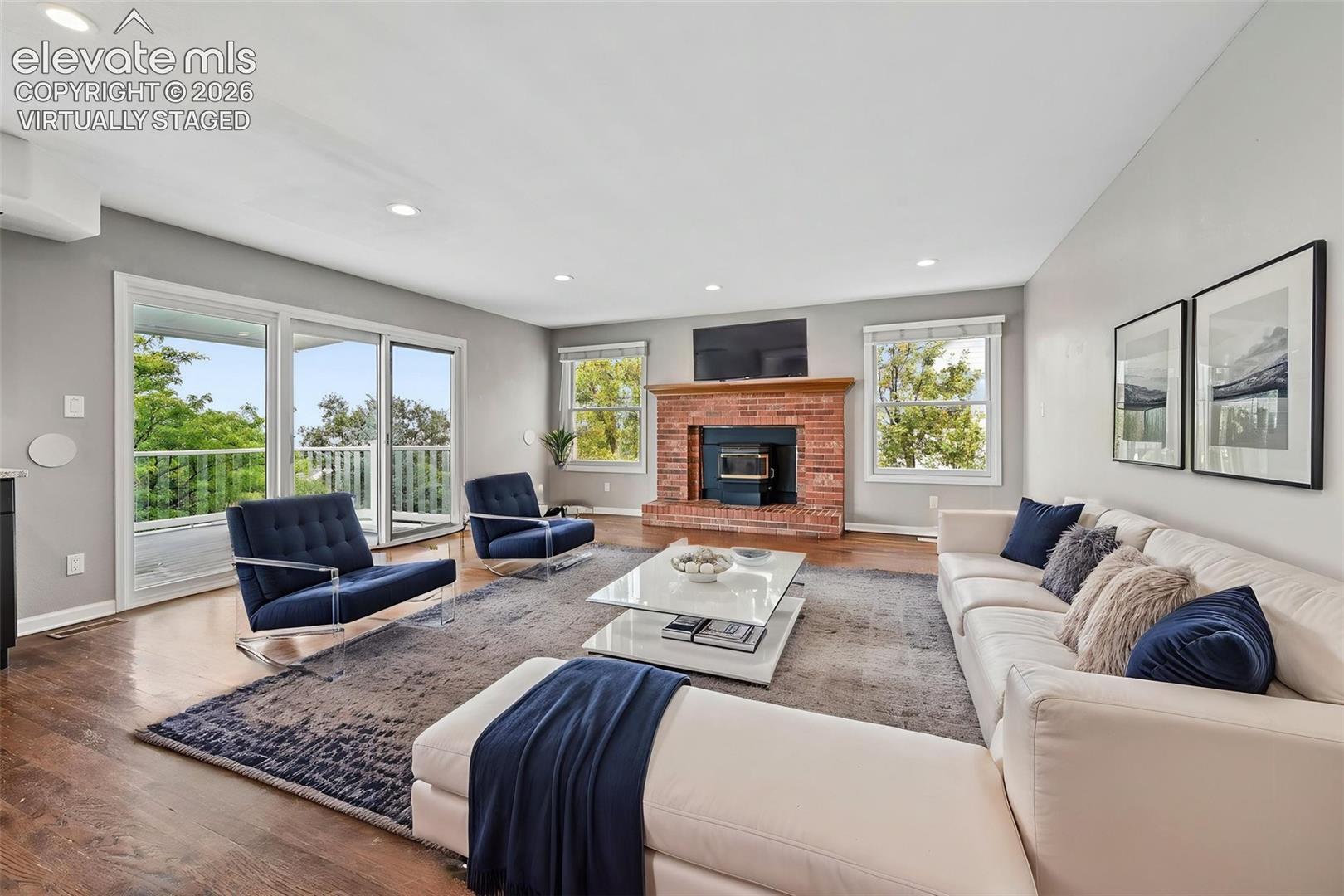 virtually staged  Family room with brick fireplace/pellet stove, adjacent to kitchen - walkout to covered large upper deck
