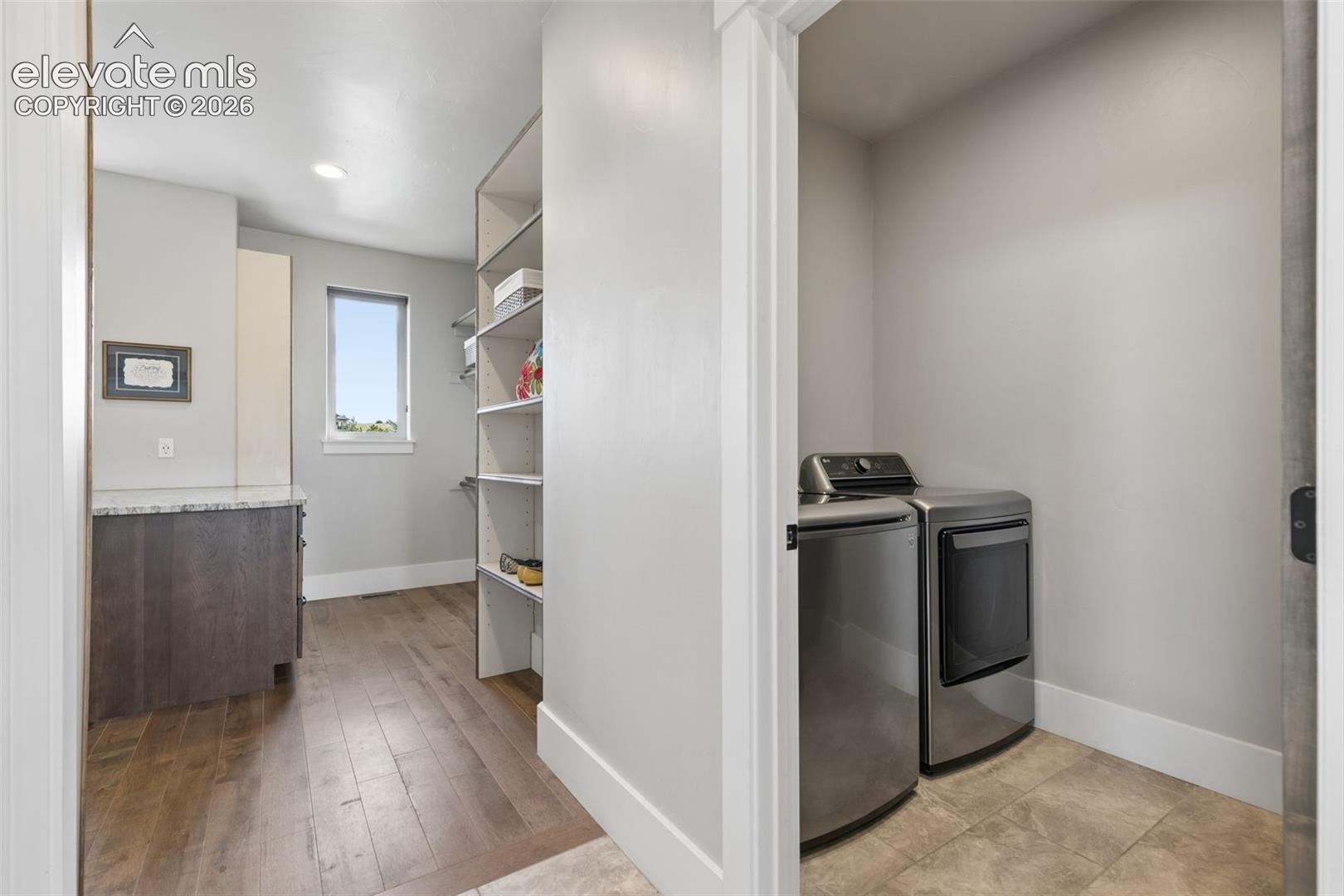 Wood-finish flooring with built-in shelving, a single window, and a stone-top cabinet