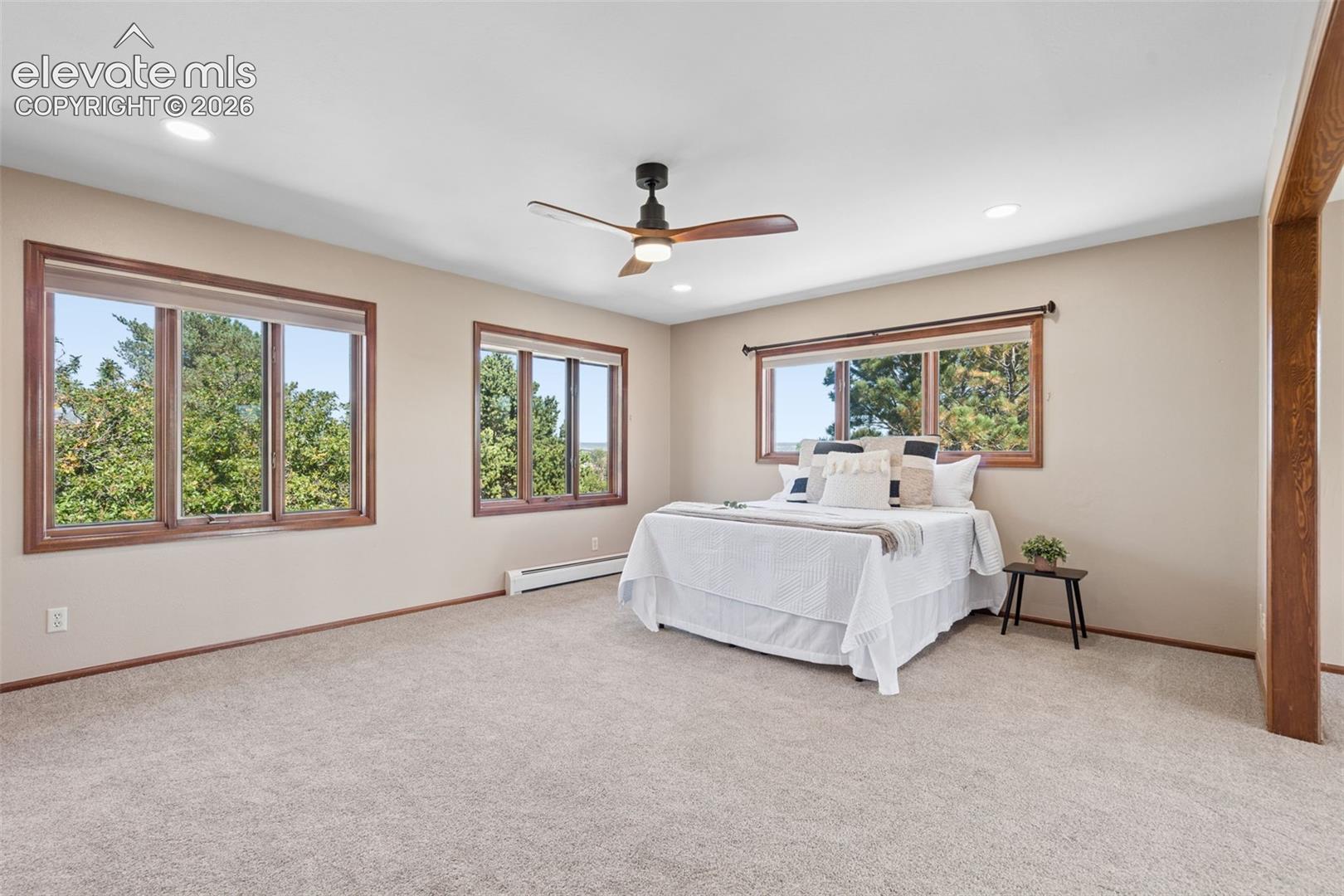 Recessed lighting, ceiling fan, and multiple windows with wood-finish trim