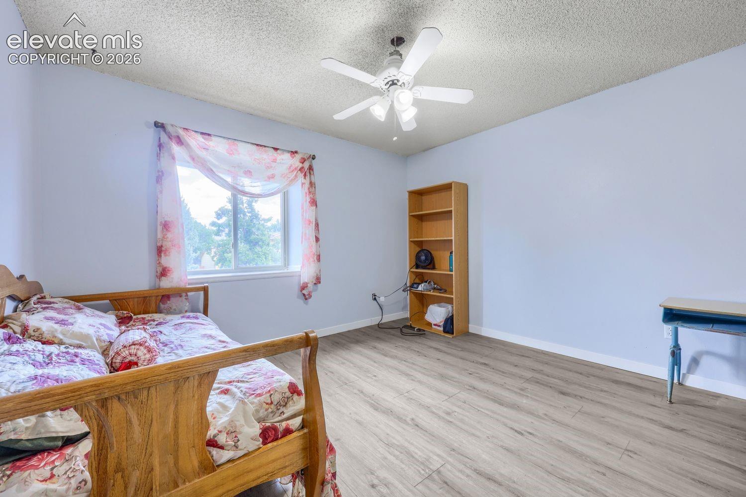 Wood-finish flooring, light-toned walls, and a ceiling fan with integrated lighting