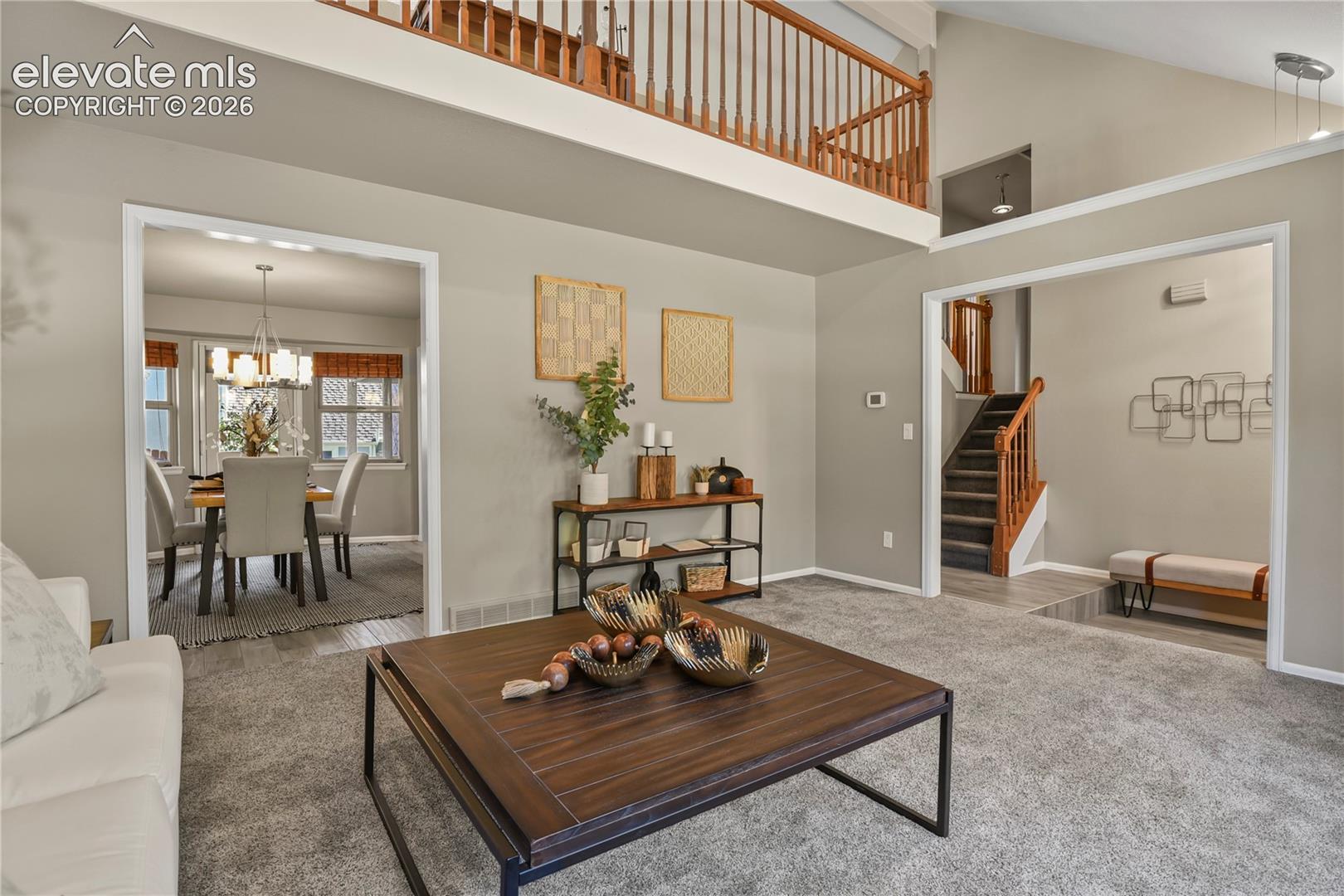 Vaulted ceilings featuring a mezzanine level with wood railings, recessed lighting, and expansive interior cased openings