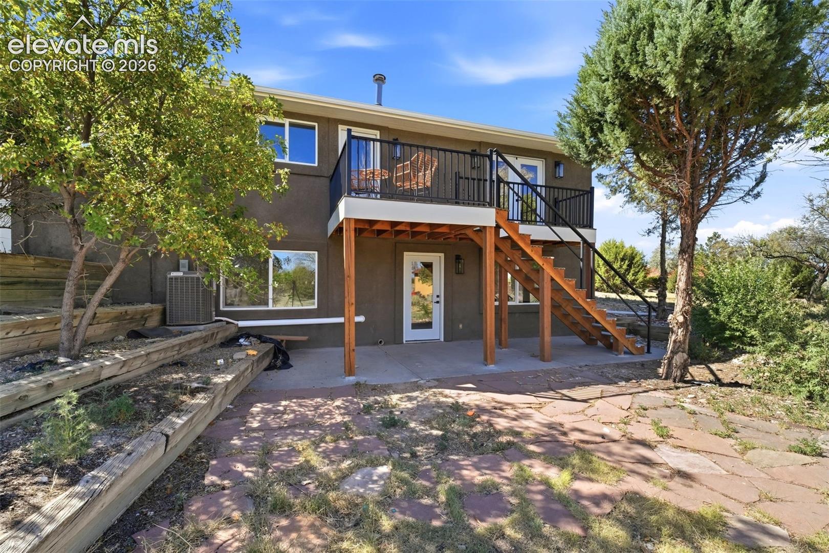 Two-story exterior with a second-level balcony featuring black metal railing and a wood staircase