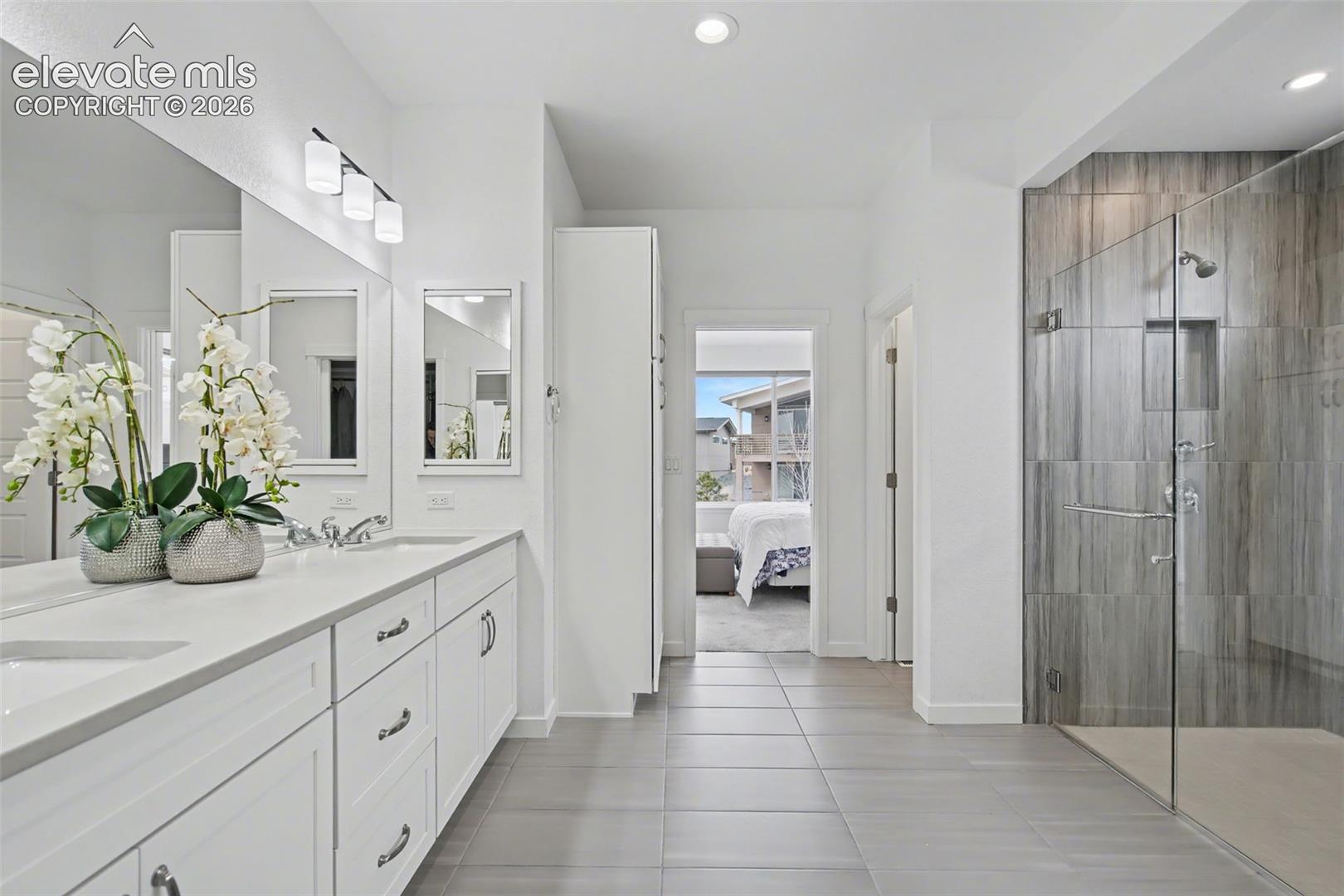 Bathroom with double vanity, ensuite bathroom, a shower stall, light tile patterned flooring, and recessed lighting
