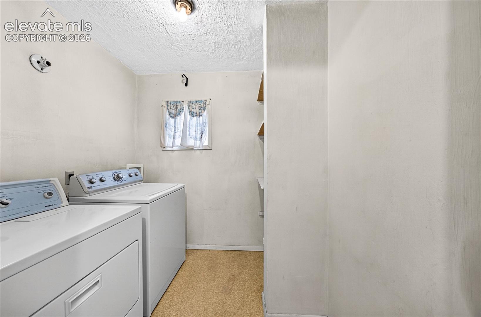 Laundry area featuring a window, and wall-mounted shelving