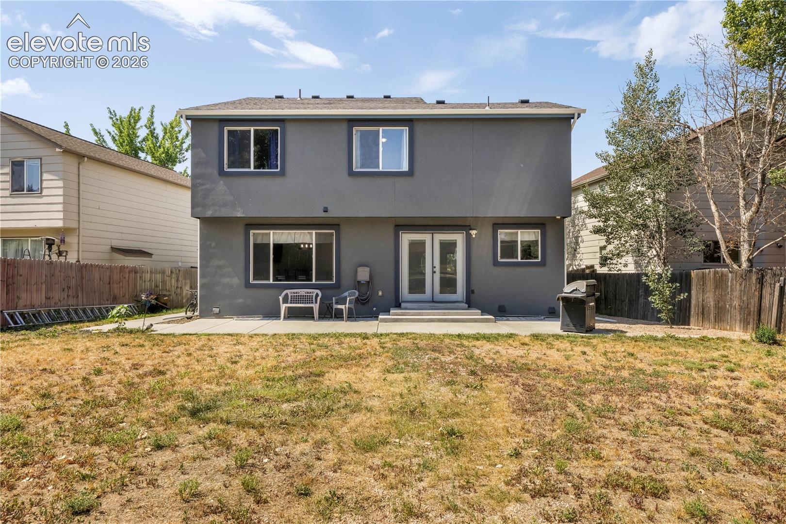 Back of home with large backyard patio, multiple levels, basketball goal and shed for storage