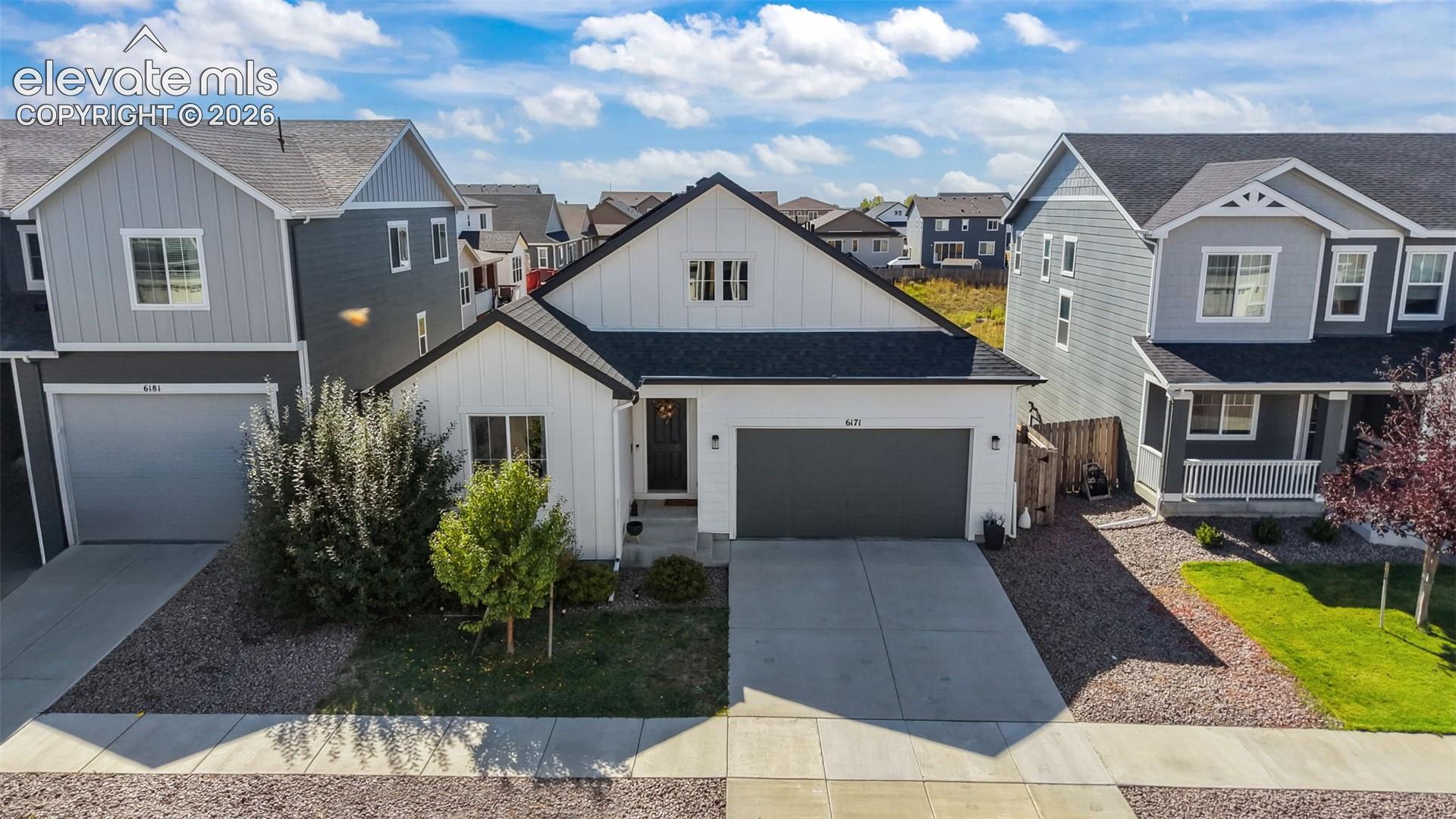 White vertical siding exterior with dark trim accents, a two-car garage, and a concrete driveway