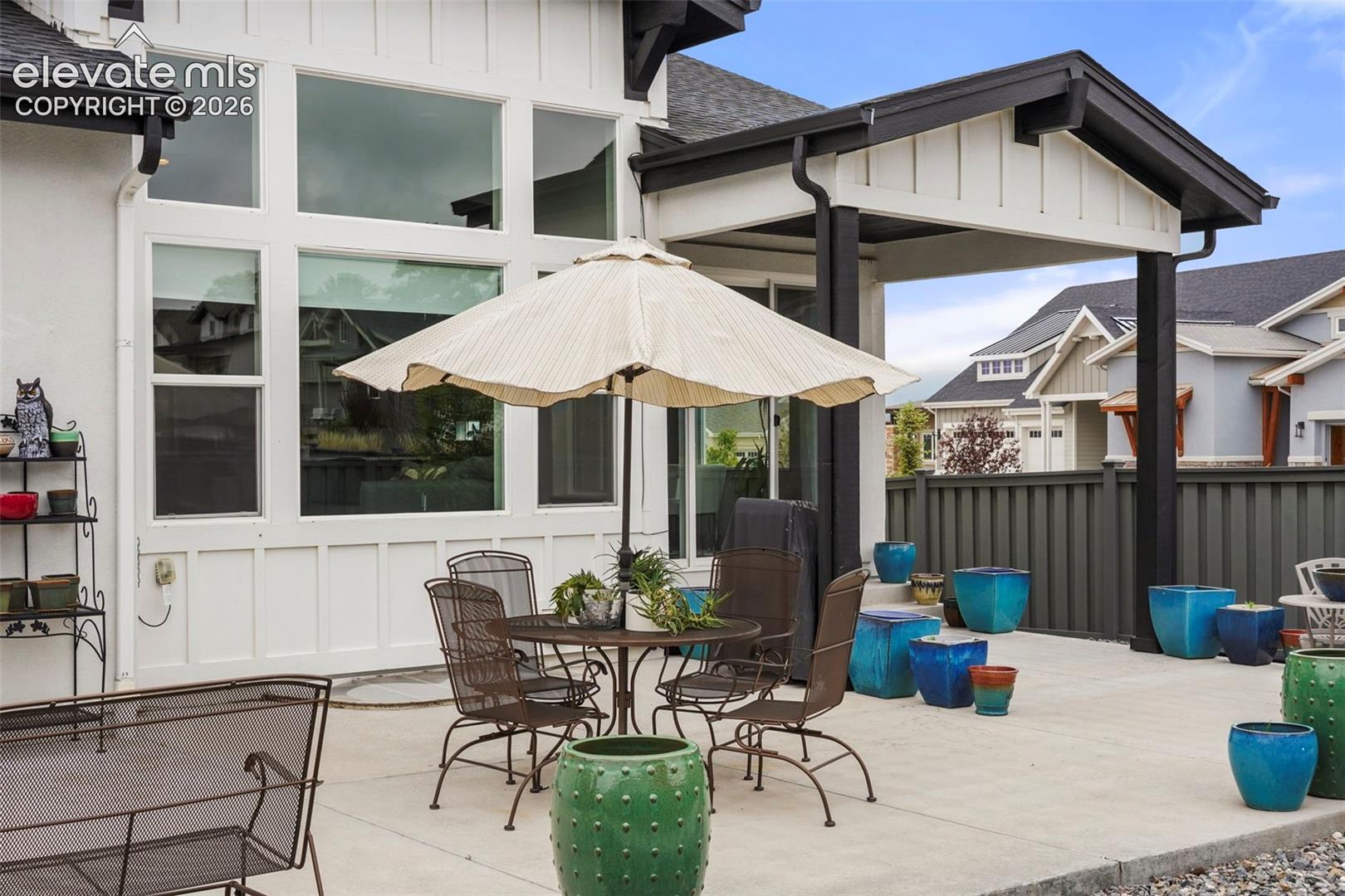 Spacious concrete patio featuring a covered outdoor area, expansive window wall, and contemporary exterior siding