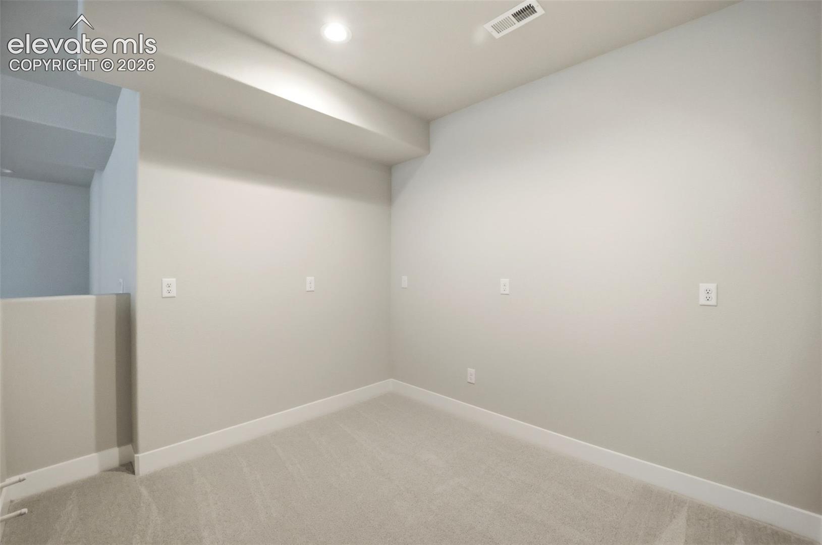 Neutral-toned interior space featuring wall-to-wall carpeting, recessed ceiling lighting, and multiple electrical outlets