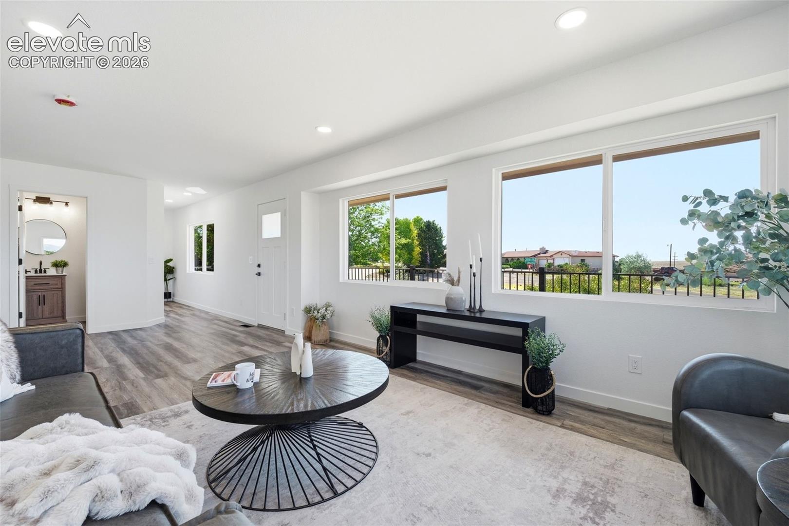 Open-concept living space featuring wood-finish flooring, recessed lighting, and multiple windows