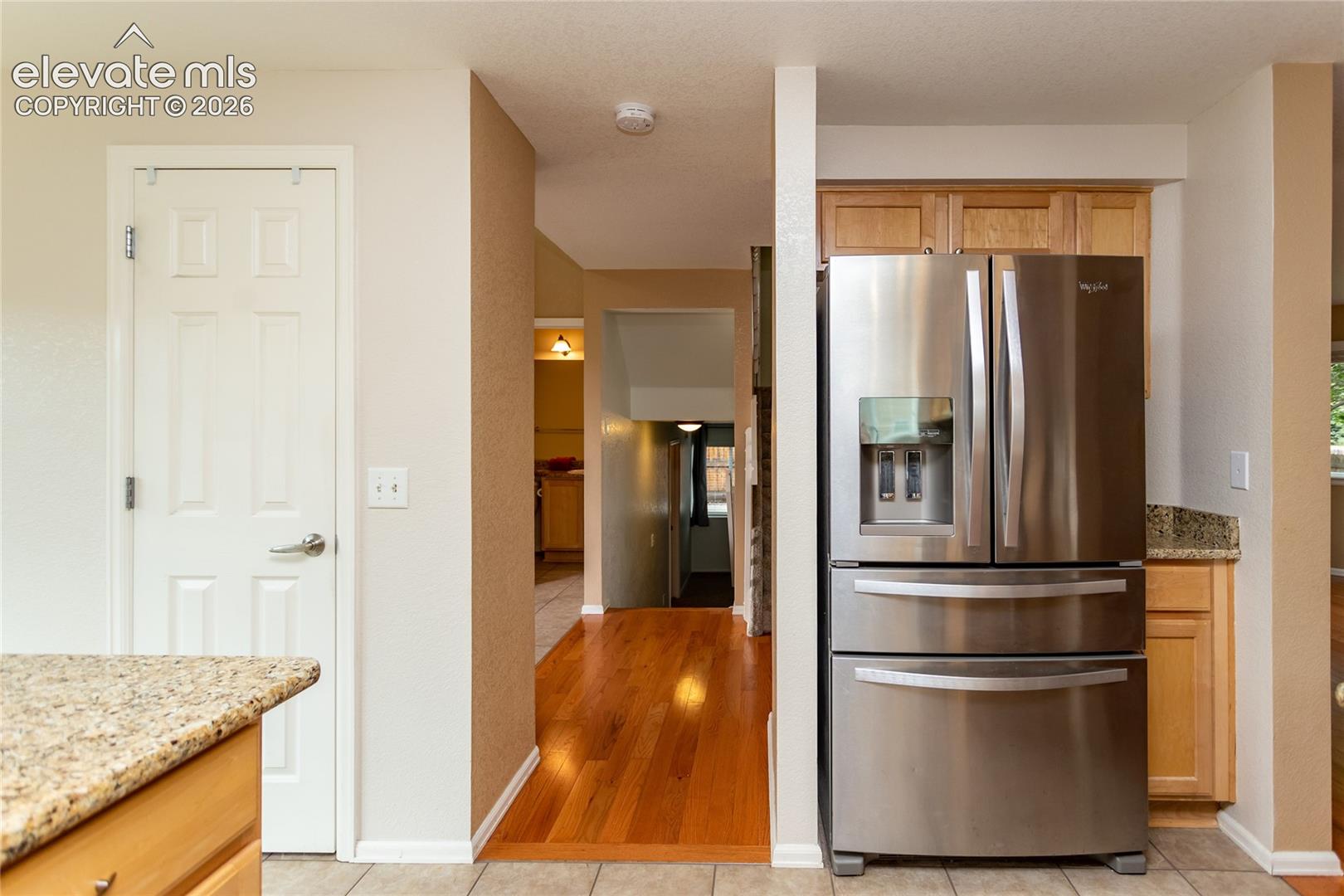 Kitchen looking to entryway featuring stainless steel French-door refrigerator