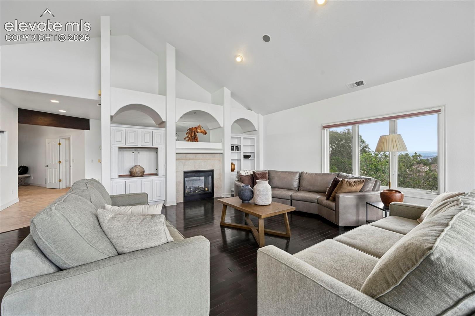 Spacious living area featuring vaulted ceilings and dark wood-finish flooring