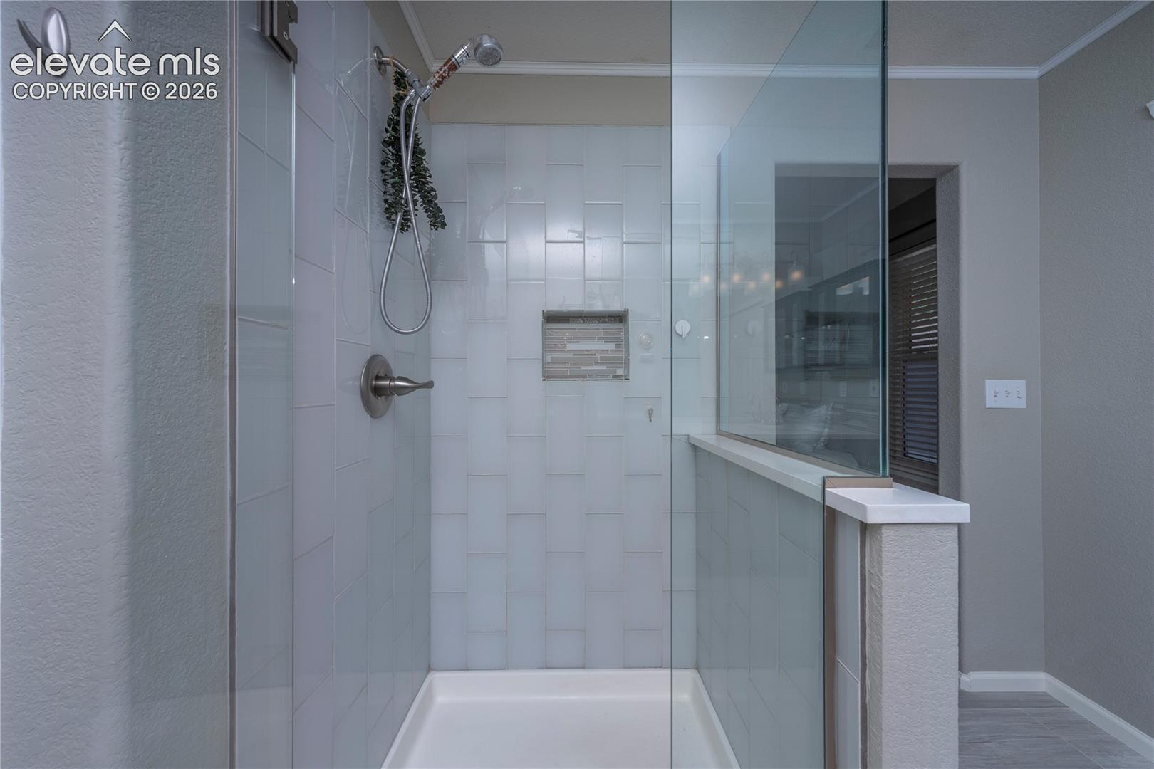 Walk-in shower featuring subway tile surround, frameless glass partition, built-in recessed storage niche, and brushed nickel hardware