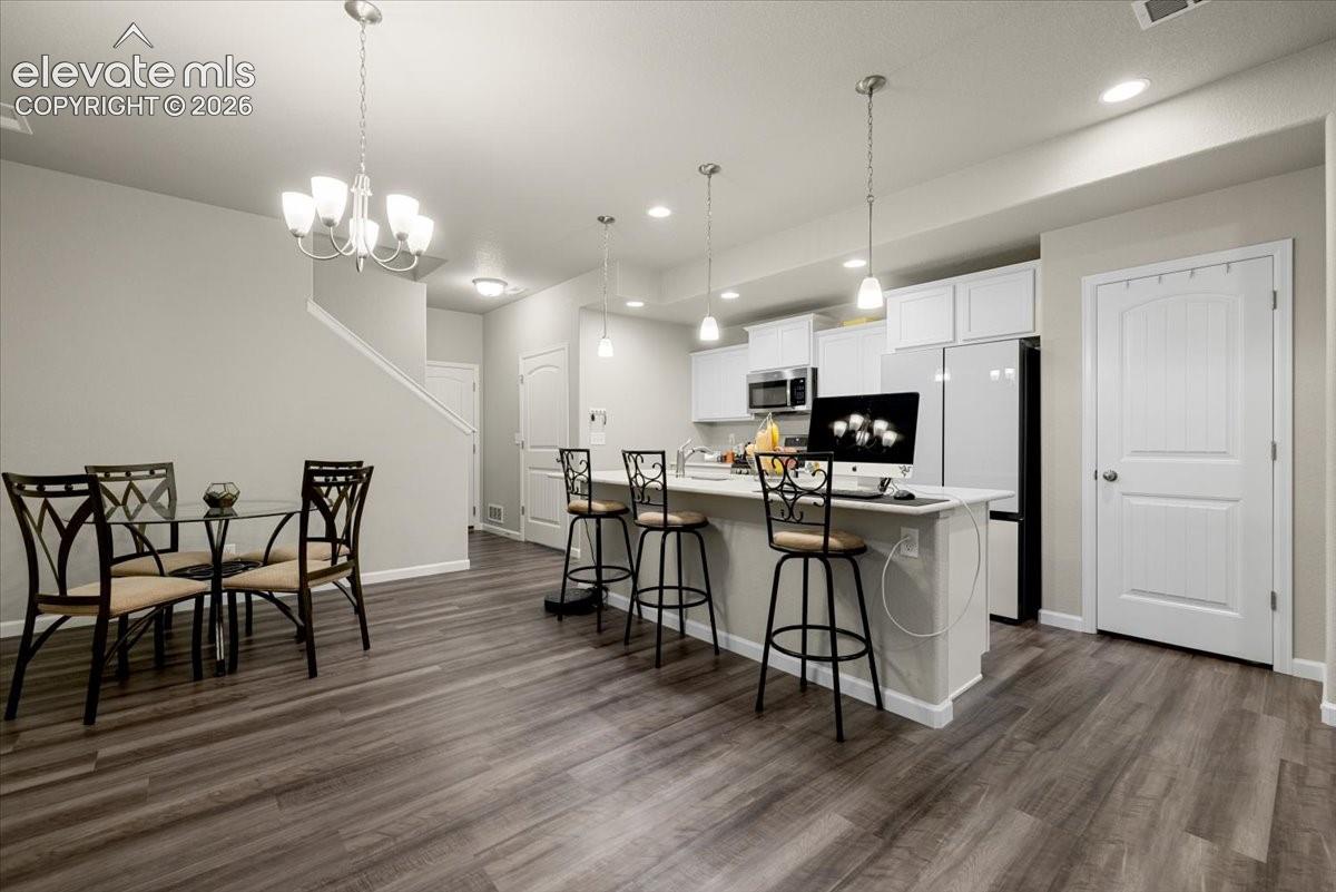 Open concept living space featuring wood-finish flooring, white cabinetry, recessed lighting, and an eat-in kitchen island