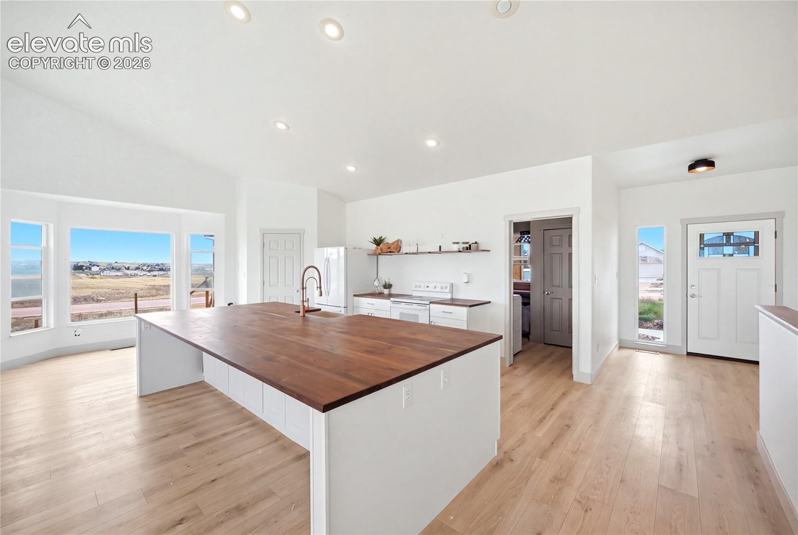 Kitchen featuring a center island with a wood countertop and undermount sink, recessed lighting, wood-finish flooring, and bay windows