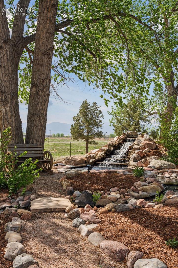 Waterfall Feature w/babbling brook and antique wheel bench in Front of Residence