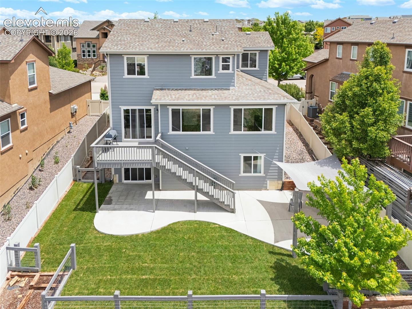 Rear exterior featuring a multi-level deck, a concrete patio, and a manicured lawn