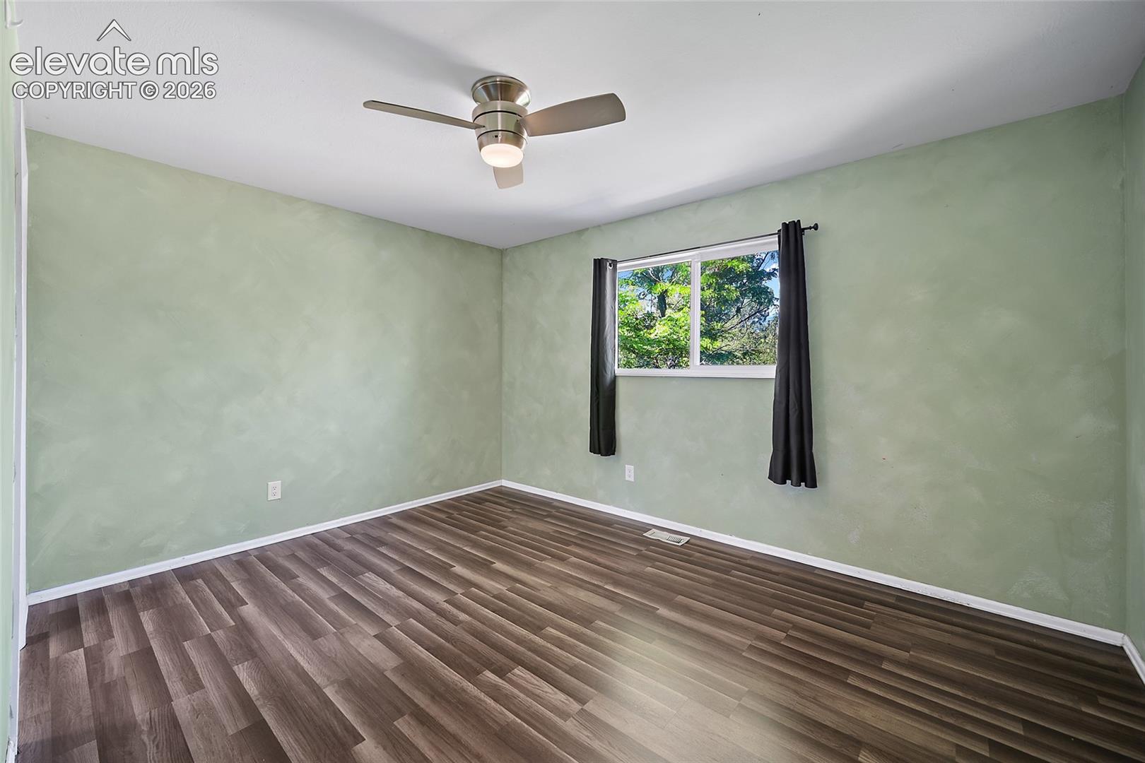 Bedroom with ceiling fan and updated flooring.