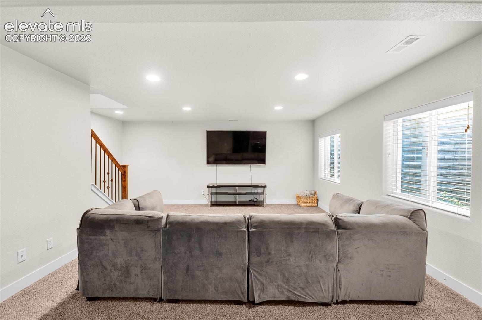 Interior space featuring recessed lighting, wall-to-wall carpeting, wood-finish stair railings, and windows with horizontal blinds