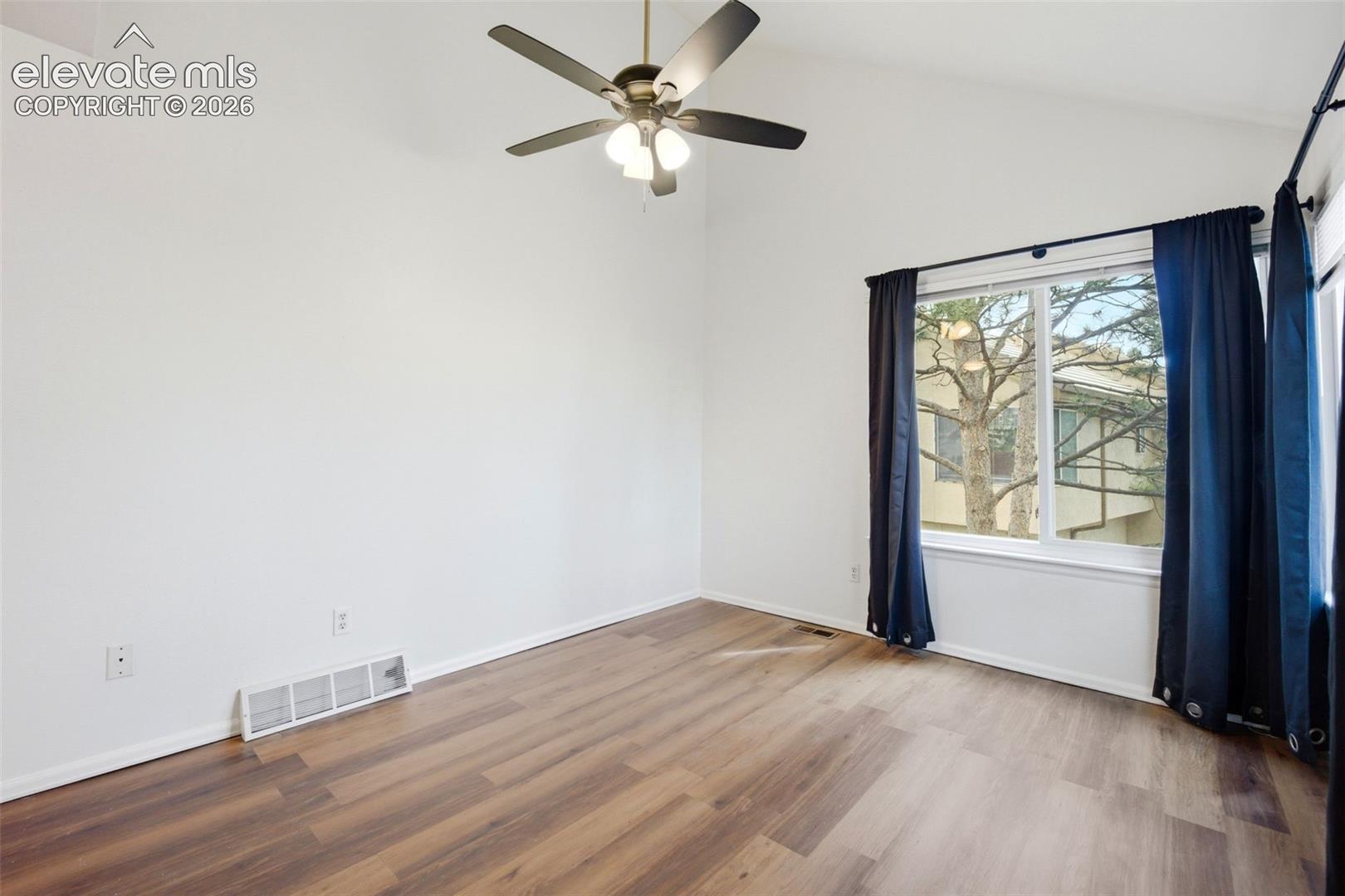 Vaulted ceilings, wood-finish flooring, and a multi-blade ceiling fan with integrated lighting