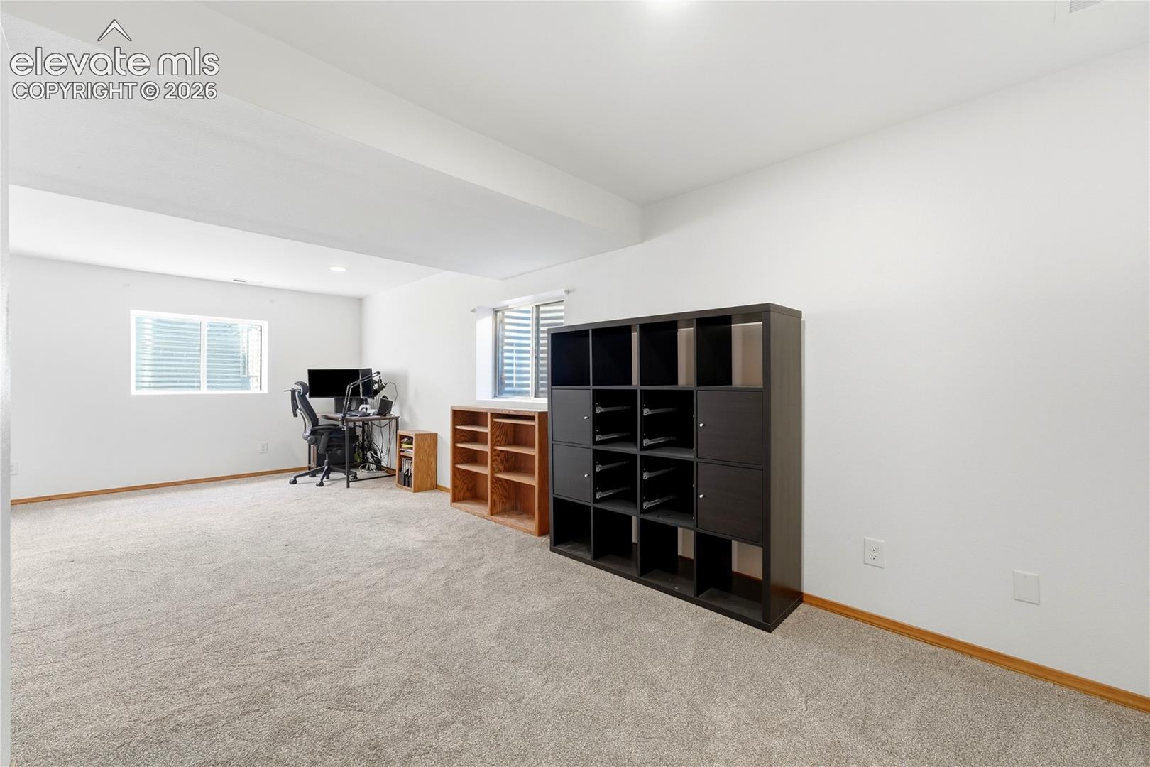 Spacious room featuring light-colored carpeting, white walls, and a window well