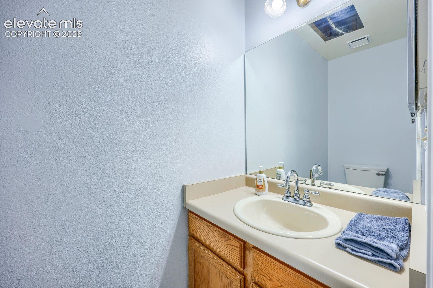 Single vanity with a laminate countertop, integrated sink, and wood-finish cabinetry