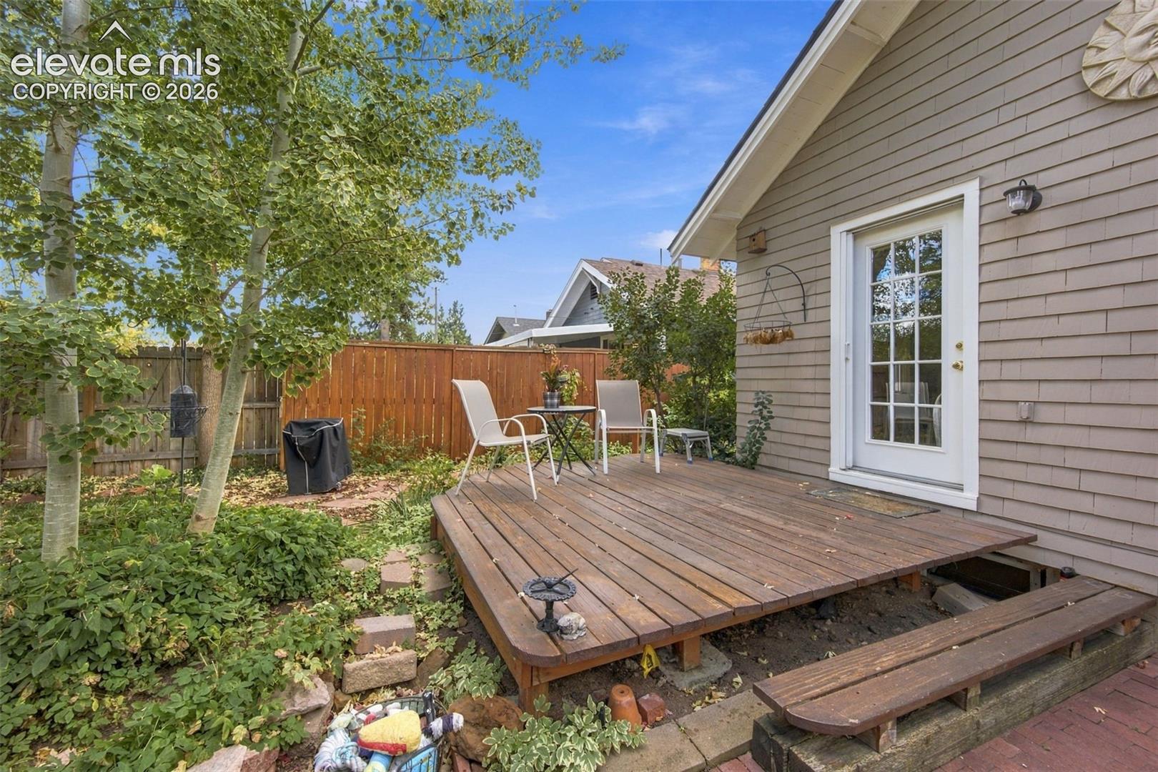 Rear exterior featuring shingle-style siding, a wooden deck with built-in bench seating, and a partial wood privacy fence