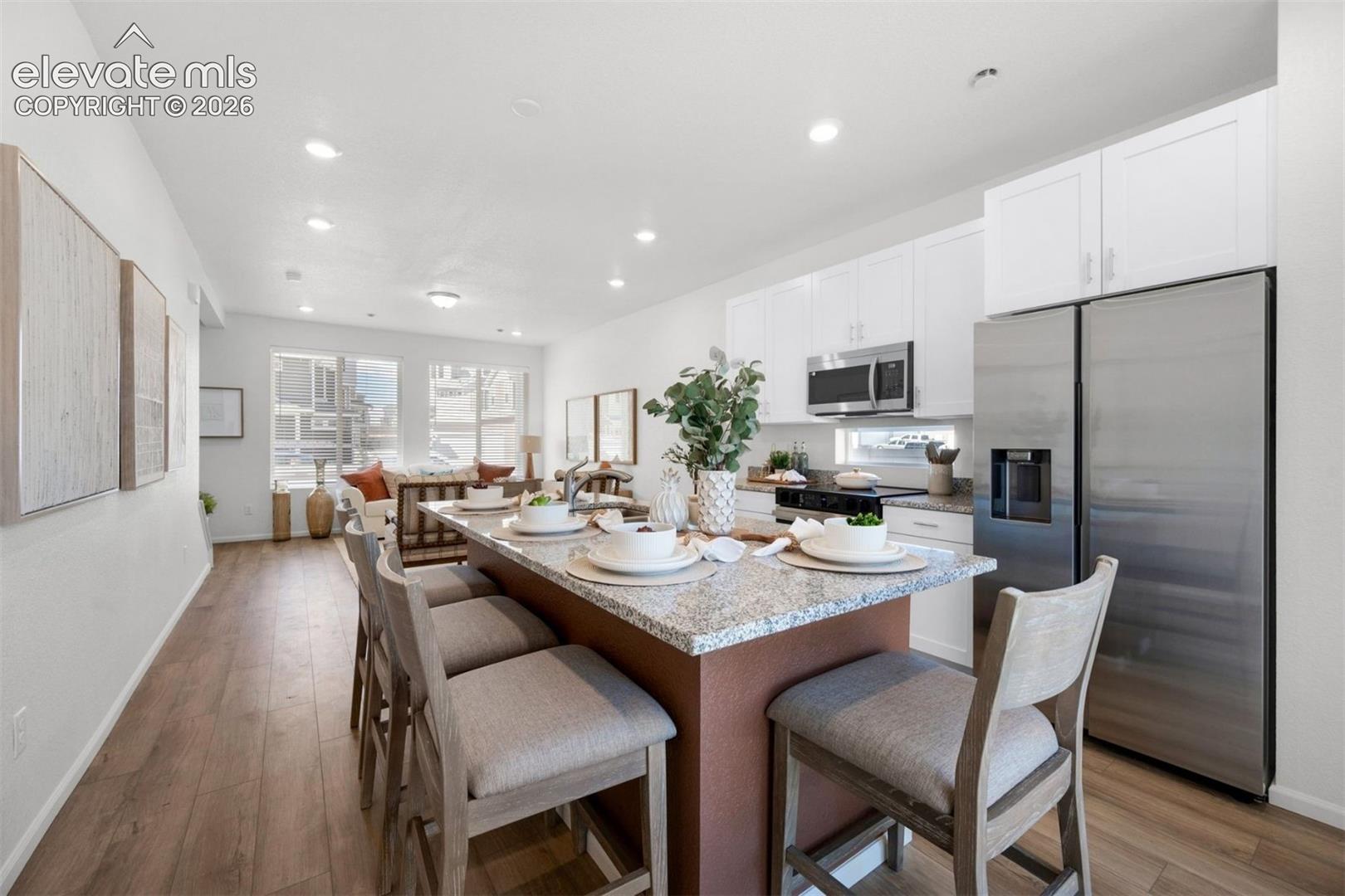 Open-concept living space featuring wood-finish flooring, recessed lighting, and large windows
*photos of a model home*