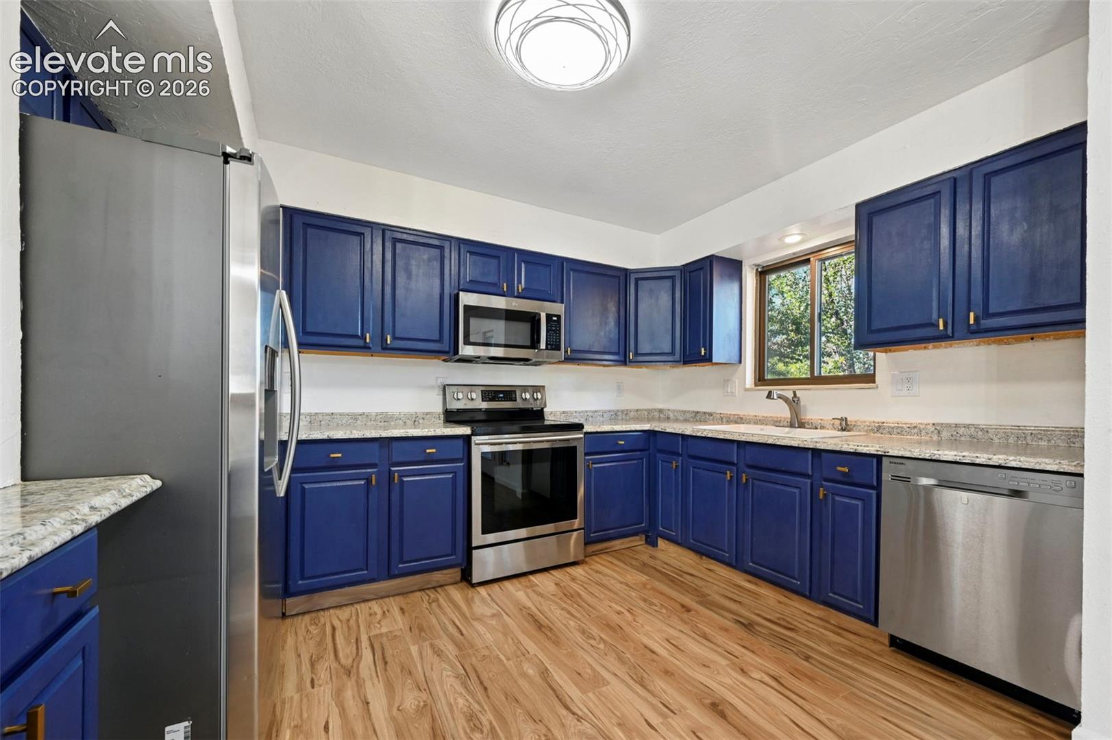 Kitchen featuring navy blue shaker-style cabinetry, formica-countertops, stainless steel appliances, new LVP flooring, and a flush-mount light fixture