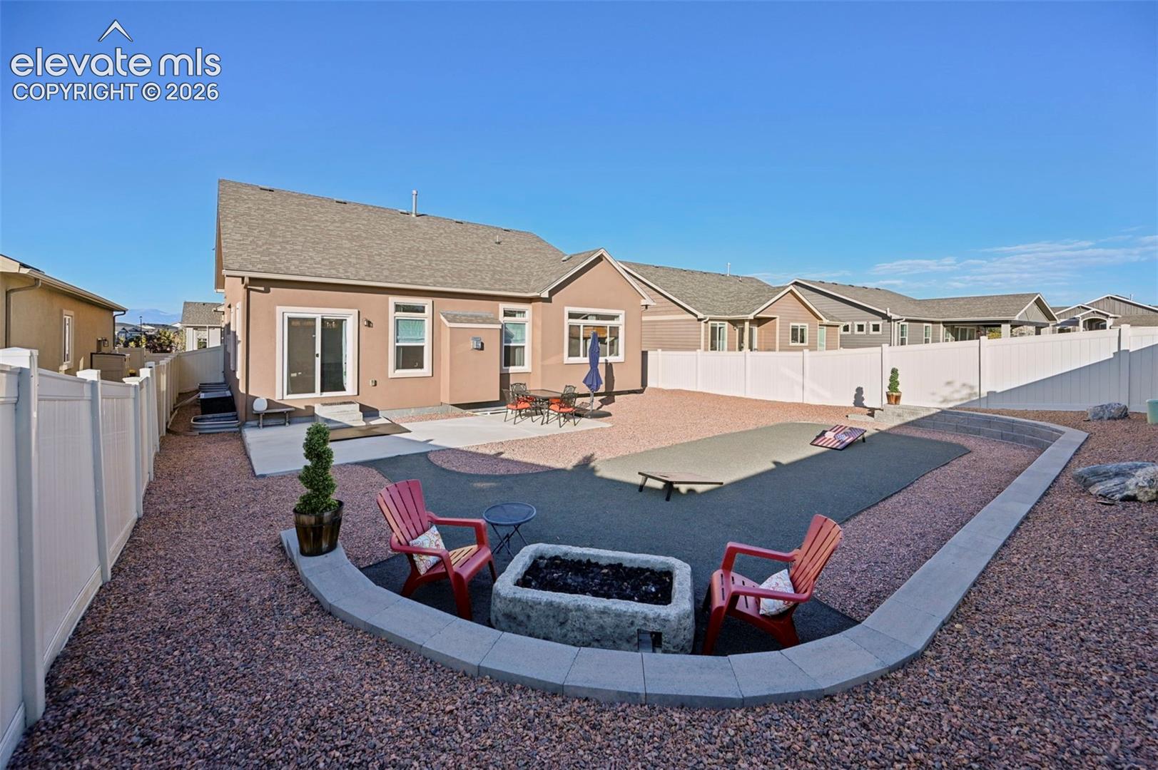 Expansive backyard featuring a gravel landscape, a concrete patio, and a dedicated fire pit area
