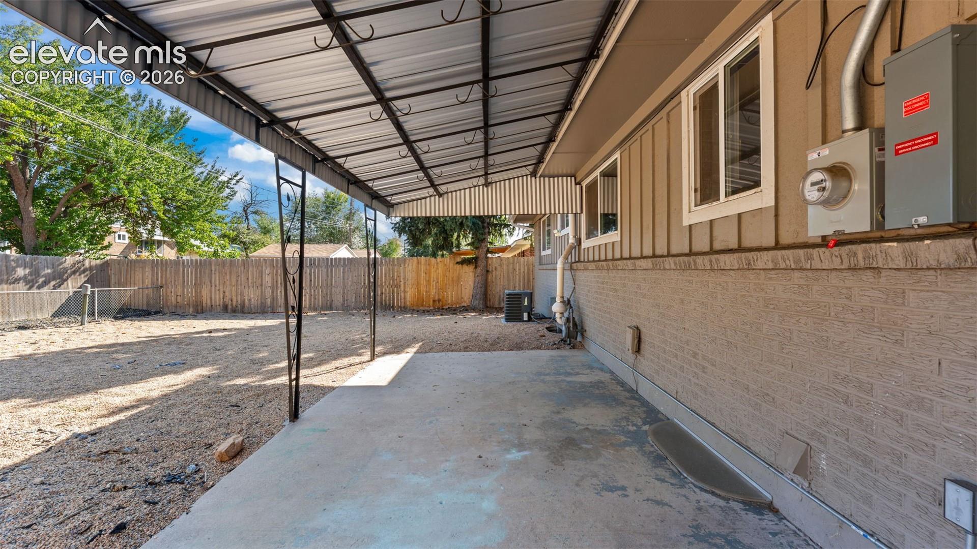 Covered patio with concrete flooring, wood siding, and a privacy fence