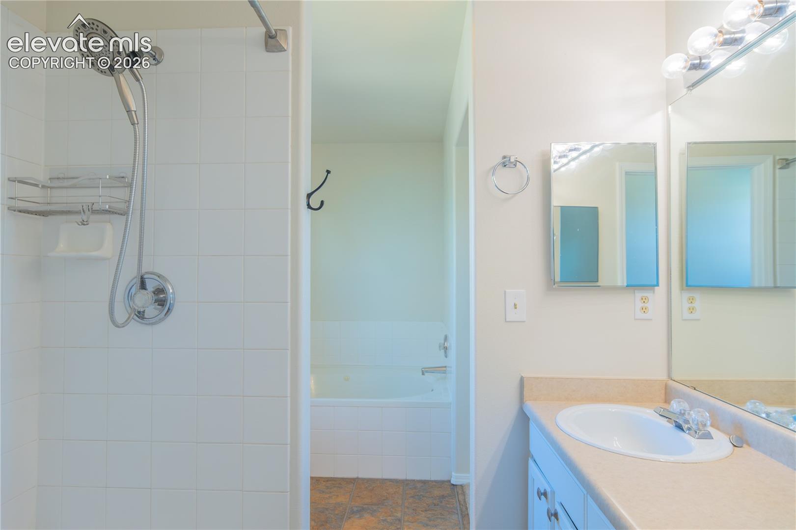 Five-piece primary bath featuring a separate tiled shower, jetted soaking tub, and dual vanities.