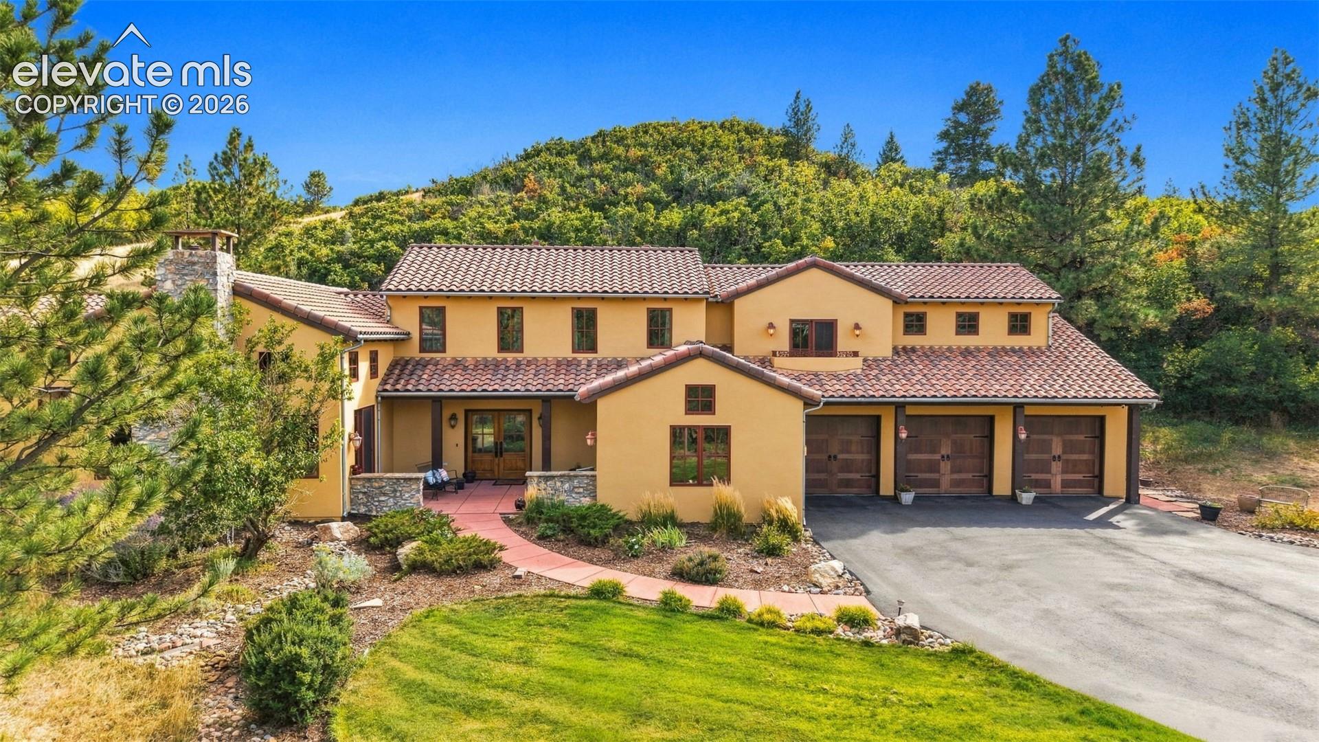 Stucco exterior with a tile roof, a three-car garage, and a paver pathway