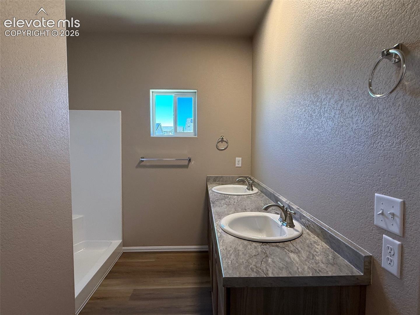 Dual undermount sinks, stone-look countertop, wood-finish vanity, and a window
