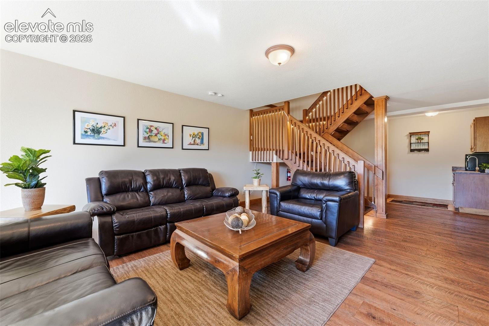 Hardwood flooring, natural wood staircase, neutral wall tones, recessed lighting, and a flush mount ceiling fixture