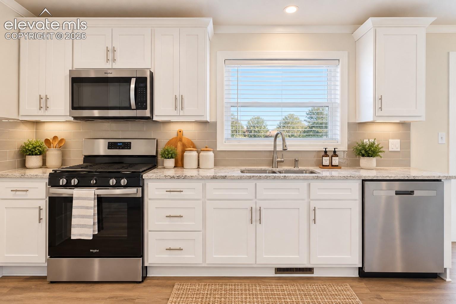 Kitchen – A closer view highlights the stainless steel range, built-in microwave, dishwasher, ample cabinetry, countertop workspace, and window above the sink.
