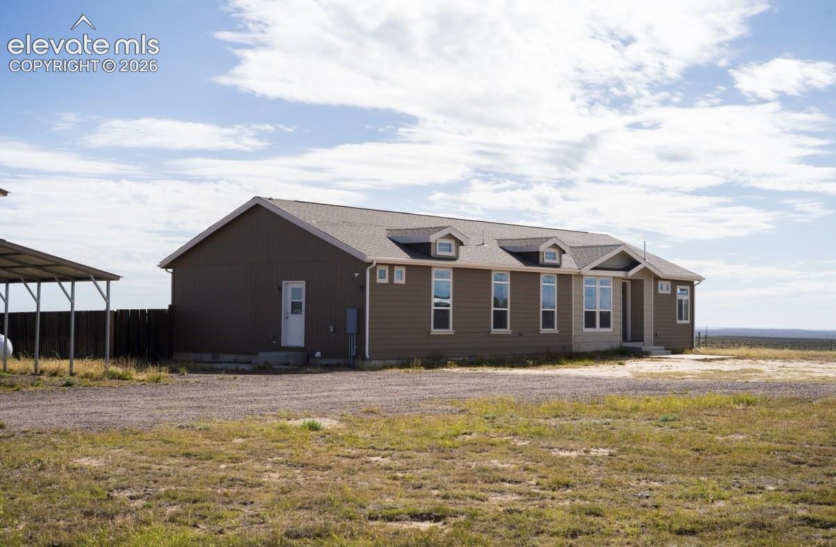 Single-story exterior featuring lap siding, asphalt shingle roofing, multiple dormer windows, and a detached metal-roofed carport