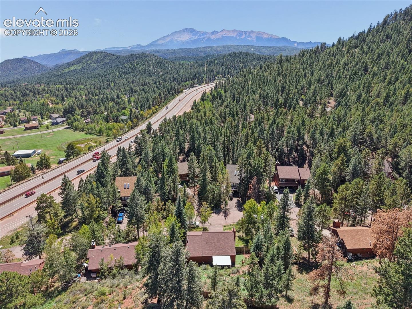 Mountain backdrop featuring a multi-lane highway, wooded landscape, and residential structures