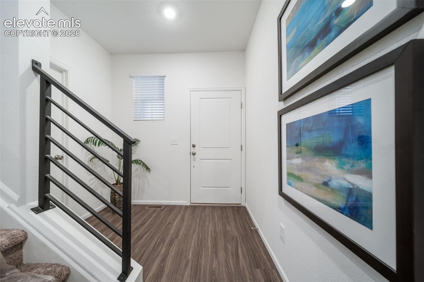 Wood-finish flooring with a white paneled door and window with blinds
*photos of a model home*