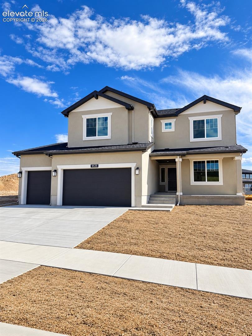 Two-story residence featuring a neutral stucco exterior, dark shingle roof, three-car garage, and concrete driveway