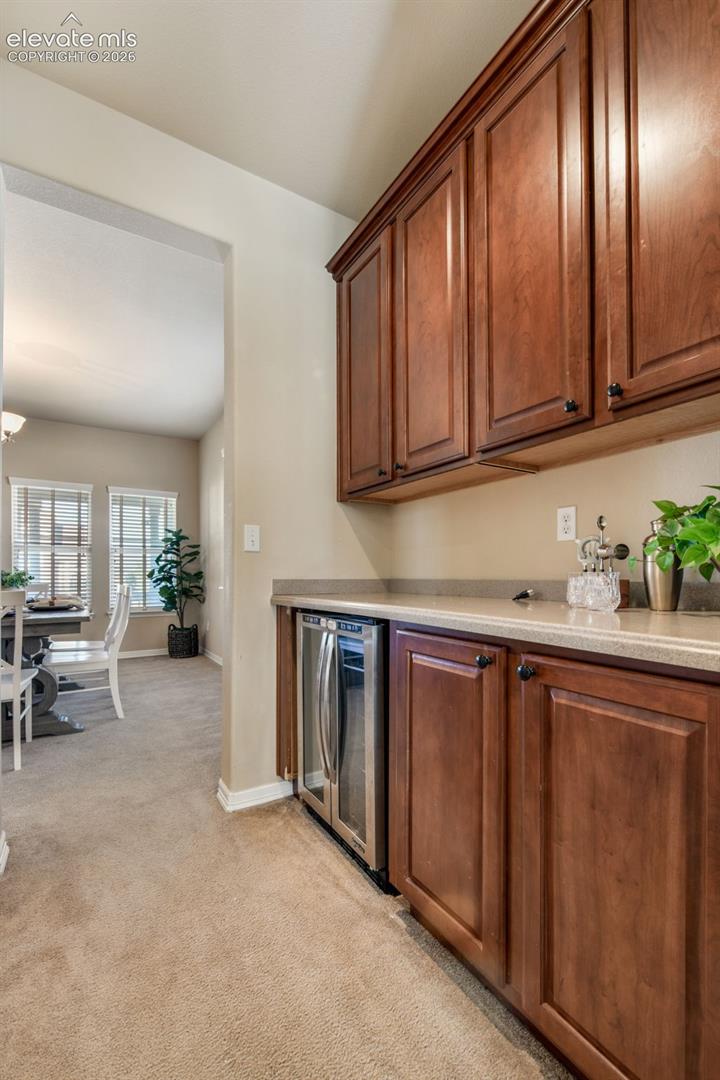 Built-in cabinetry with a beverage cooler, stone-finish countertop, and carpeted flooring