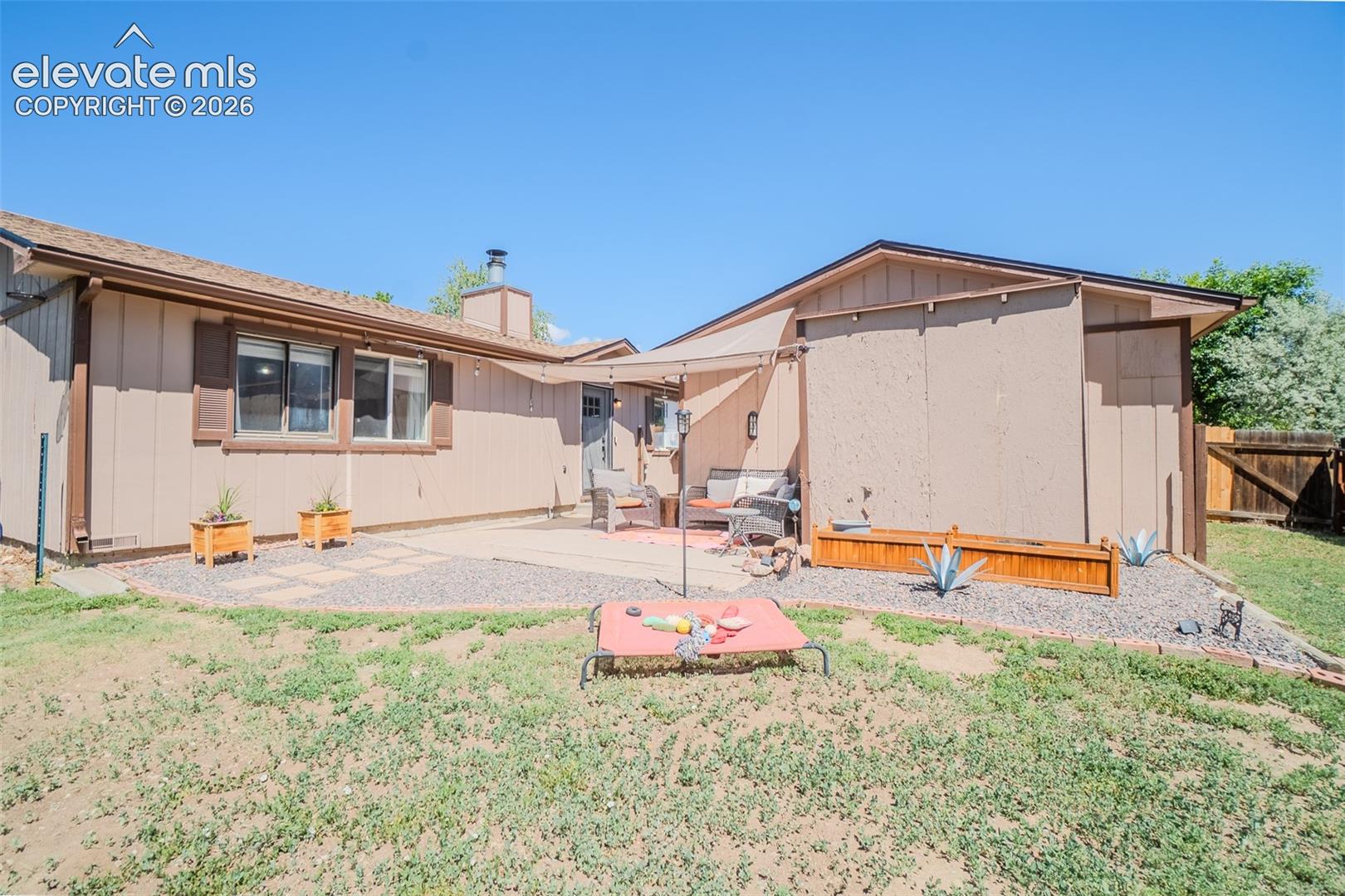 Private backyard featuring a concrete patio, gravel landscaping, and a partial wood fence