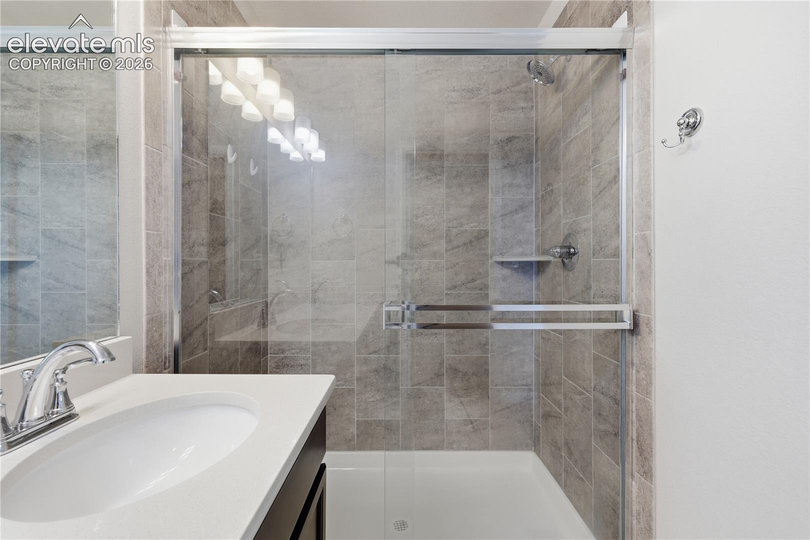 Bathroom featuring a shower with glass enclosure, tiled walls, and a built-in shelf