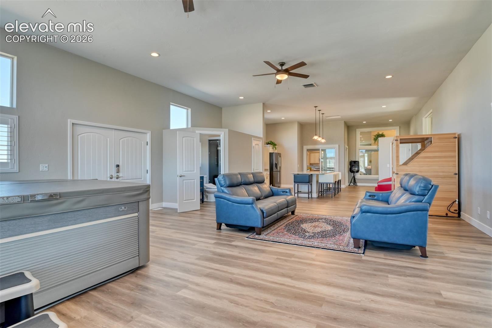 Spacious family room with wood-finish flooring, recessed lighting, a ceiling fan, sauna, steam shower, hot tub that walks out to backyard.