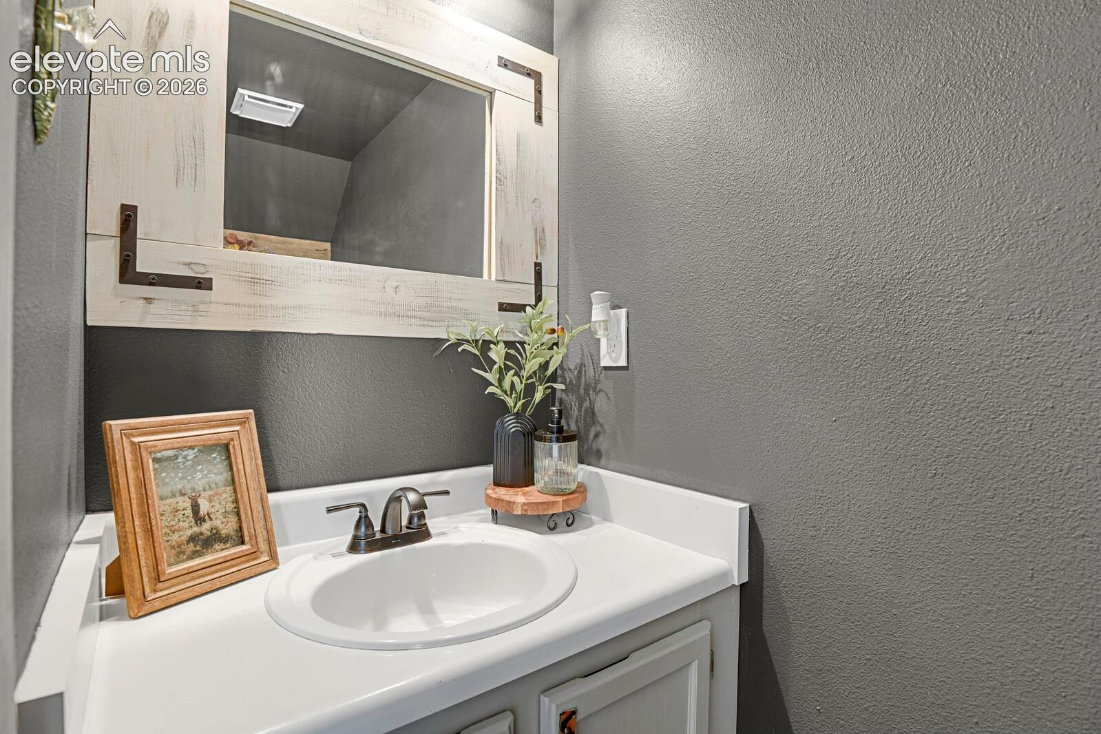 Vanity with an integrated sink, dark bronze-finish faucet, and a decorative framed mirror