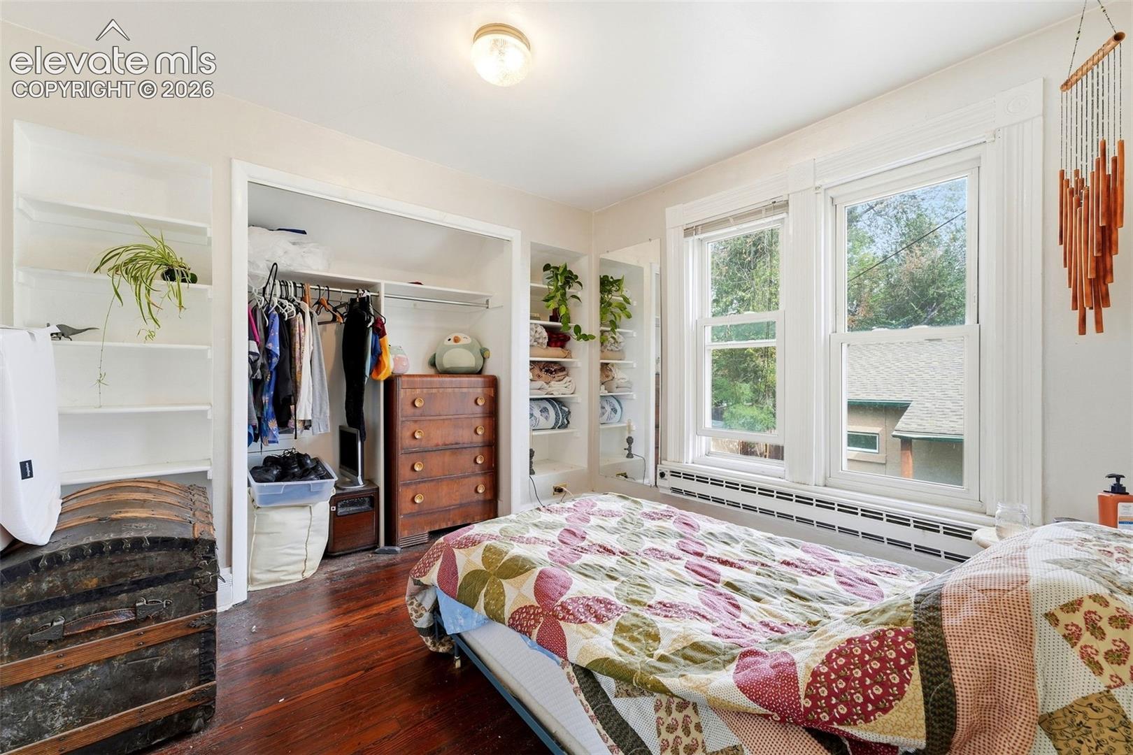Wood-finish flooring, built-in shelving, dual windows, and an integrated closet