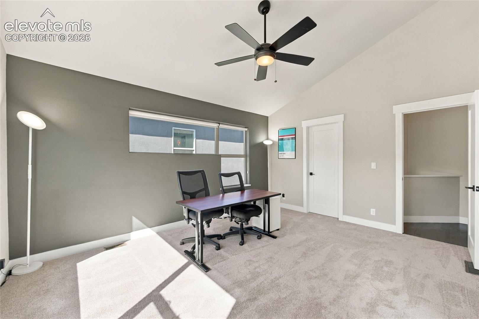 Vaulted ceilings, carpeted flooring, accent wall, and ceiling fan with integrated lighting