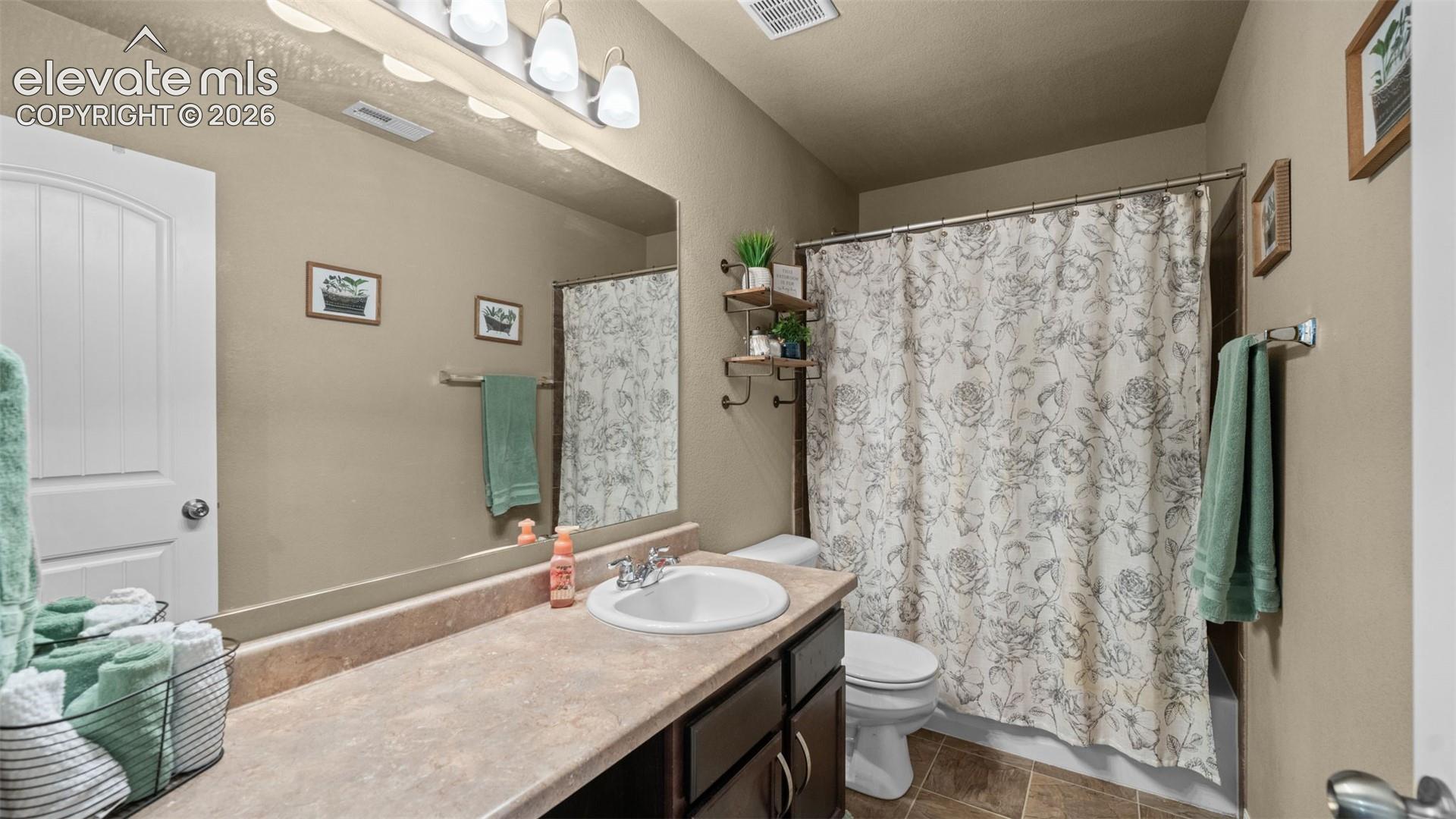 Bathroom featuring a vanity with an integrated sink, broad countertop, and dark wood-finish cabinetry